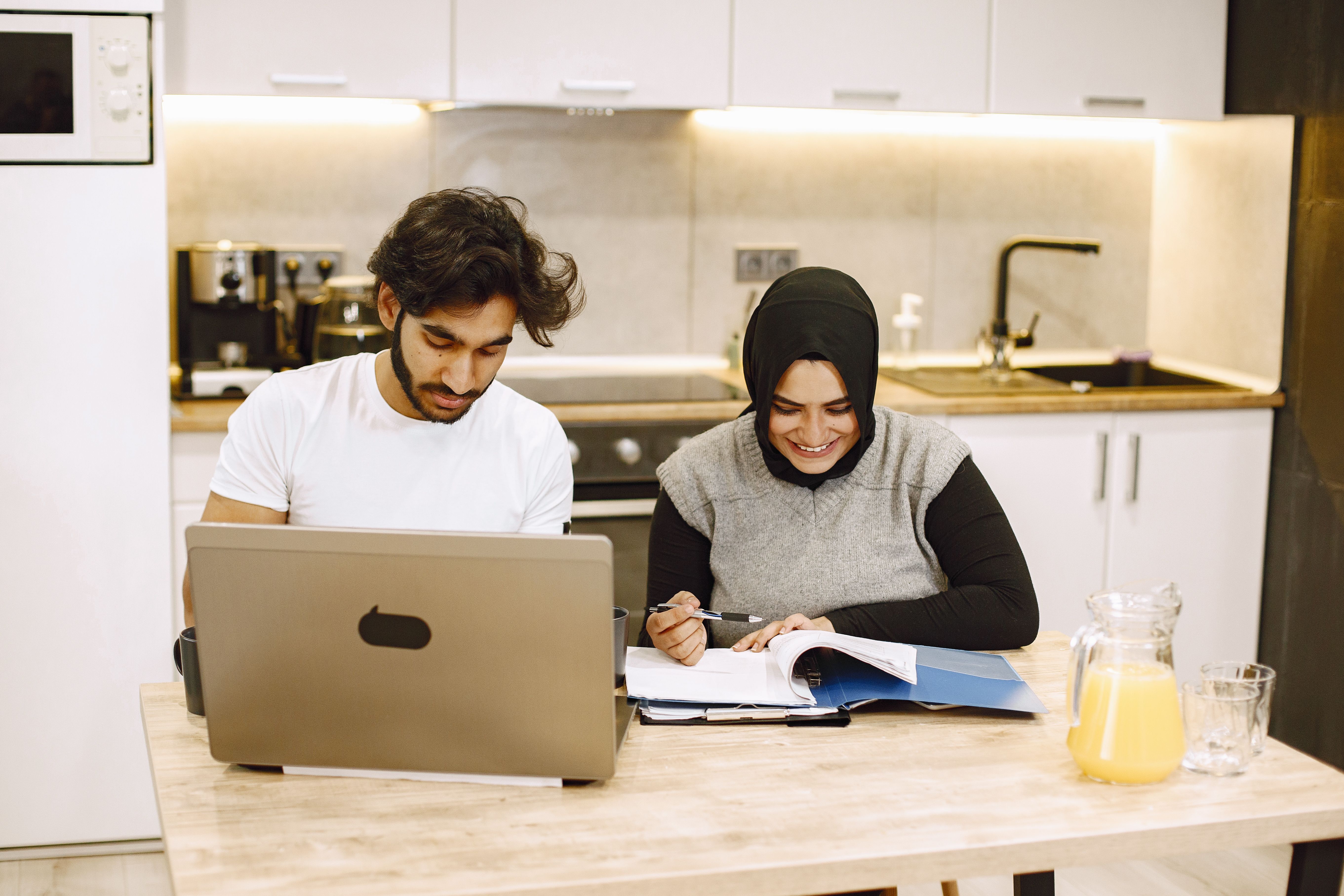 Couple travaillant ensemble sur des documents financiers et un ordinateur portable dans une cuisine